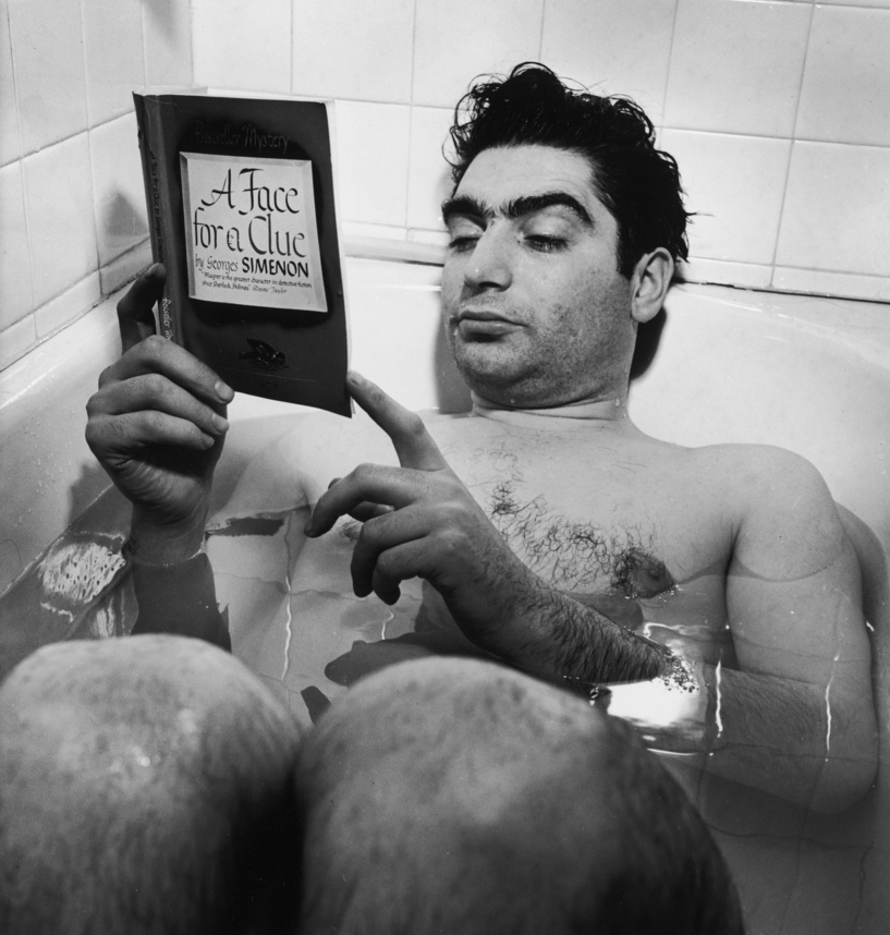 Robert Capa reading in the bathtub (New York, 1942) by Myron Davis